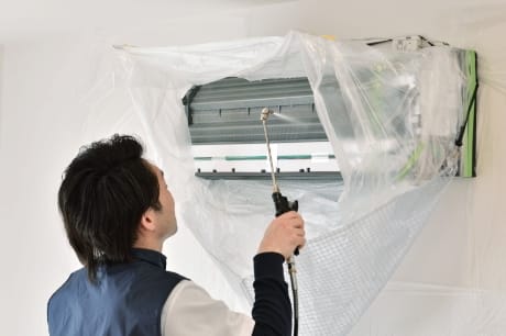 エアコン内部の洗浄作業をするスタッフの画像